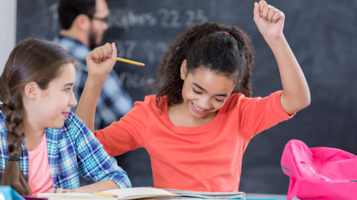 A student celebrates while studying with a classmate in a classroom